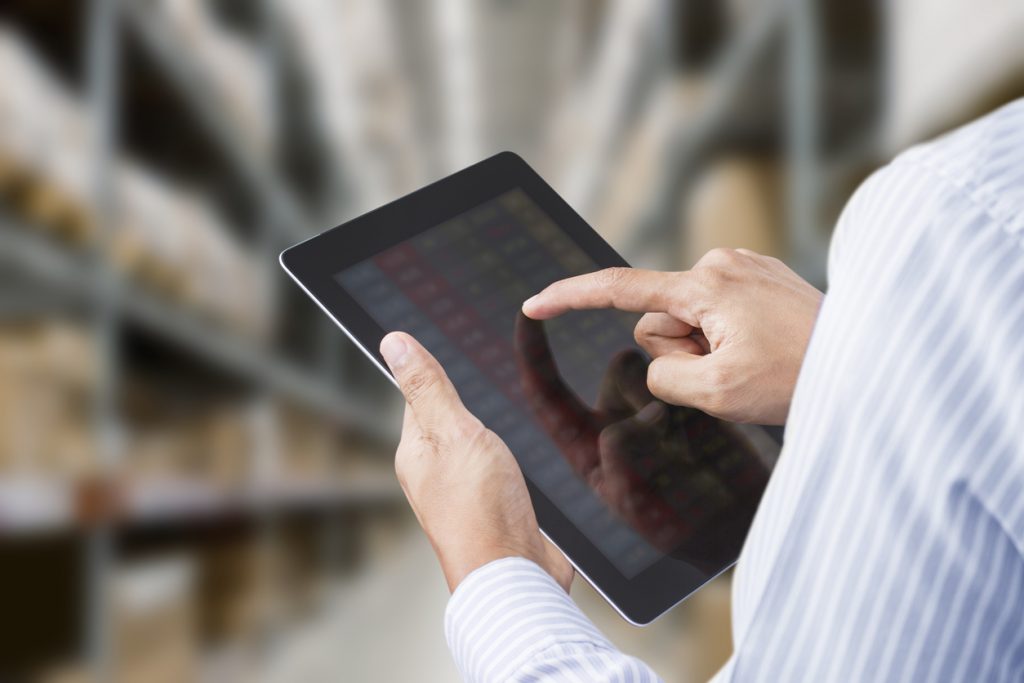 Businessman checking inventory in stock room on touchscreen tablet